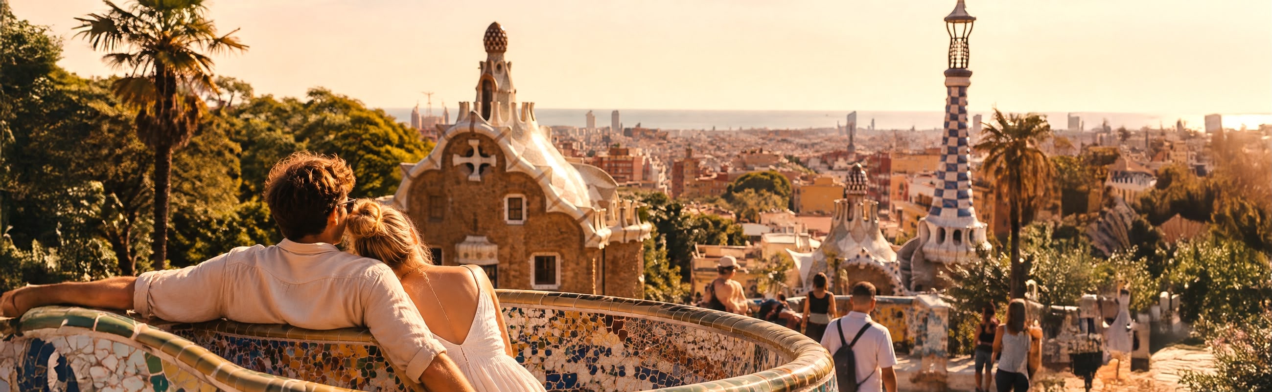 Two travellers on the mosaic bench at Park Güell, looking out over Barcelona in the late afternoon
